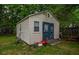 Storage shed with charming blue doors, set in a backyard with surrounding trees and fence at 8053 Duralee Ln, Douglasville, GA 30134