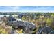 An aerial view reveals beautiful homes nestled amongst vibrant greenery near a tranquil lake under a bright sky at 1125 Lake Shore Overlook, Alpharetta, GA 30005