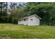 White outbuilding on a grassy lawn surrounded by trees, offering additional storage or workspace at 317 Community Sw Dr, Mableton, GA 30126
