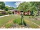 Landscaped front yard with green grass, flowers, and mature trees surrounding a charming brick home at 243 Woodview Ln, Smyrna, GA 30082