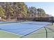 Well-maintained tennis court surrounded by tall trees, ready for recreational play at 5034 Hickory Hills Dr, Woodstock, GA 30188