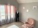 Cozy bedroom with natural light, neutral decor, and a stylish accent chair and ottoman at 220 Baltimore Ave, Stockbridge, GA 30281