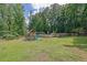 Sprawling backyard featuring a playground, lush greenery, and partial fencing at 7155 Bannister Park Ln, Cumming, GA 30028