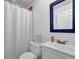 Updated bathroom with white vanity, a blue-framed mirror, and shower with white shower curtain at 7155 Bannister Park Ln, Cumming, GA 30028