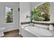 A relaxing soaking tub area with a large window providing scenic backyard views at 7155 Bannister Park Ln, Cumming, GA 30028