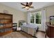 Cozy bedroom with a twin bed, bookshelf, ceiling fan, and bright window view at 7155 Bannister Park Ln, Cumming, GA 30028