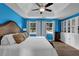 Blue main bedroom featuring a tray ceiling, ceiling fan, and built-in white cabinets for storage at 7155 Bannister Park Ln, Cumming, GA 30028