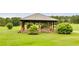 Open-air pavilion with stone columns on a grassy lawn surrounded by flowering bushes at 10213 Tall Pine Ct, Villa Rica, GA 30180