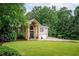 Elegant home featuring a stone facade, arched entryway, lush lawn, and a private driveway leading to an attached garage at 3290 Coachmans Ne Way, Roswell, GA 30075