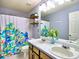 Bathroom with double sinks, shower with colorful patterned curtain, and decor shelving at 566 Lullingstone Se Dr, Marietta, GA 30067