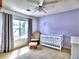 Bedroom room with lavender walls, neutral-colored carpet, white crib and armchair at 566 Lullingstone Se Dr, Marietta, GA 30067