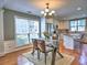 Bright dining area with hardwood floors, a glass table, chandelier, and an open view of the kitchen at 566 Lullingstone Se Dr, Marietta, GA 30067