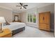 Relaxing bedroom with neutral tones, plush carpet, ceiling fan, dresser, and a large window with natural light at 580 Cliftwood Ct, Sandy Springs, GA 30328