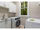 Well-lit laundry room includes a sink with marble countertop, sleek white cabinets, and modern washer/dryer units at 580 Cliftwood Ct, Sandy Springs, GA 30328