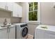 Laundry room featuring modern washer and dryer units, cabinets, and a window overlooking the yard at 580 Cliftwood Ct, Sandy Springs, GA 30328