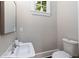 Clean powder room shows marble-style sink, commode, window, neutral color scheme, and framed mirror at 580 Cliftwood Ct, Sandy Springs, GA 30328