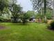A picturesque backyard with a sprawling green lawn, mature trees, and a glimpse of the home with a back deck at 910 Oriole Se Ln, Marietta, GA 30067