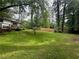 A serene backyard featuring lush green grass, mature trees, a wood fence, and a charming back deck at 910 Oriole Se Ln, Marietta, GA 30067