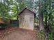 Rustic wooden storage shed with double doors nestled among trees and foliage in the backyard at 910 Oriole Se Ln, Marietta, GA 30067