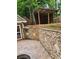 Wood backyard storage building with access to a brick patio with a stone retaining wall at 2320 Glynmoore Dr, Lawrenceville, GA 30043