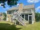 Exterior view of the house featuring a large deck, stairs, screened in patio, and grassy yard at 775 Brand South Trl, Lawrenceville, GA 30046