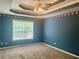 A blue-painted bedroom with a brown carpet, trey ceiling, ceiling fan, and a large window at 775 Brand South Trl, Lawrenceville, GA 30046