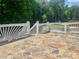 View of the deck with a stone floor, white railing and stairs with lush green foliage in the background at 775 Brand South Trl, Lawrenceville, GA 30046