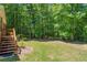 A grassy yard adjoins to wooded area at this home with a back porch and stairs at 415 Stephanie Ct, Stockbridge, GA 30281