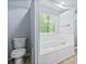 A neutral bathroom features a toilet and separate garden tub under a window at 740 Marcus Nyah Ct, Atlanta, GA 30349