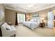 Comfortable bedroom featuring a tray ceiling, large windows, a sitting area, and neutral tones at 10090 Jones Bridge Rd # 2, Alpharetta, GA 30022
