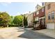 Street view of brick townhomes with two-car garages in a tree-lined community at 10090 Jones Bridge Rd # 2, Alpharetta, GA 30022