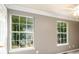 Bedroom with tan walls and two large windows overlooking lush green foliage at 3001 Majestic Park Ct, Duluth, GA 30096