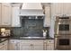 Close-up of a kitchen featuring custom cabinetry, a mosaic backsplash, and stainless steel appliances at 3680 Milton Park Dr, Alpharetta, GA 30022