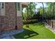 Secluded backyard featuring artificial turf, brick details, and privacy fencing surrounded by lush greenery at 44 Barbara Ln, Atlanta, GA 30327