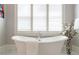 Bright bathroom featuring a luxurious soaking tub, white flowers, and natural light from the plantation shutters at 44 Barbara Ln, Atlanta, GA 30327