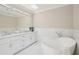 Elegant bathroom features a soaking tub, double vanity with white marble counters and white tile at 1059 Woodland Ave, Atlanta, GA 30316