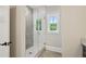 Bright bathroom features glass shower with gray and white tile, white trim window, and wood look flooring at 1059 Woodland Ave, Atlanta, GA 30316