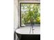 Luxurious bathroom with a soaking tub beneath a large window and marble tile at 187 Clay Se St, Atlanta, GA 30317