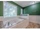 Large soaking tub next to a bright window in the bathroom at 2492 Bermuda Dr, Loganville, GA 30052