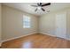Neutral bedroom featuring a ceiling fan, hardwood floors, window and white door at 2492 Bermuda Dr, Loganville, GA 30052