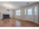 Bright and spacious living room featuring a brick fireplace, elegant chandelier, and beautiful hardwood floors at 2492 Bermuda Dr, Loganville, GA 30052