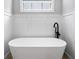 Modern bathroom featuring freestanding tub, wainscotting, black fixtures, and neutral tile floor at 1010 Fendley St, Woodstock, GA 30188