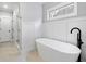 Modern bathroom featuring freestanding tub, wainscotting, black fixtures, and neutral tile floor at 1010 Fendley St, Woodstock, GA 30188