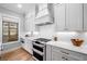Well-lit kitchen boasting white cabinets, a stylish range hood, and modern appliances at 1010 Fendley St, Woodstock, GA 30188