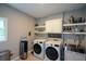 Modern laundry room with stainless steel sink, floating shelves, and front-load washer and dryer at 3295 Waters Ml, Alpharetta, GA 30022