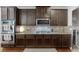 A kitchen featuring a gas stovetop, stainless steel microwave and ovens, granite countertops, and ample dark brown cabinetry at 2906 Jones Phillips Rd, Dacula, GA 30019