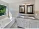 Bright bathroom features double sink vanity, soaking tub, decorative tile work and window views at 3479 Woodruff Ridge Ln, Loganville, GA 30052