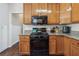 Galley kitchen features wooden cabinetry, granite countertops, and black appliances at 3725 Falls Trl, Winston, GA 30187