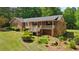 Brick home featuring a covered porch, mature trees, and landscaped yard at 19 Margrit Ct, Stockbridge, GA 30281