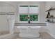 Bright bathroom featuring a freestanding tub, glass enclosed shower, and a window with a lush green view at 4550 Lois Se St, Smyrna, GA 30080